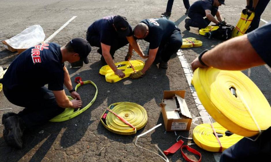 Cal Fire firefighters pack hoses to fight wildfires at the Ventura County Fairgrounds fire camp during the Thomas fire in Ventura, California, U.S. December 12, 2017. Image: Patrick T Fallon, Reuters