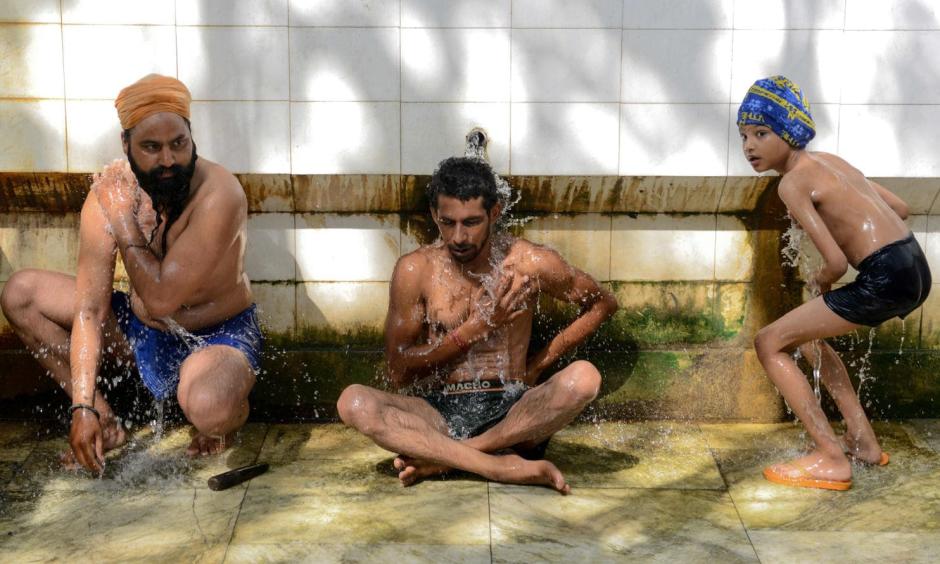 Two Indian men and a boy cool off in Amritsar, India, on Tuesday. Photo: Narinder Nanu, AFP/Getty Images