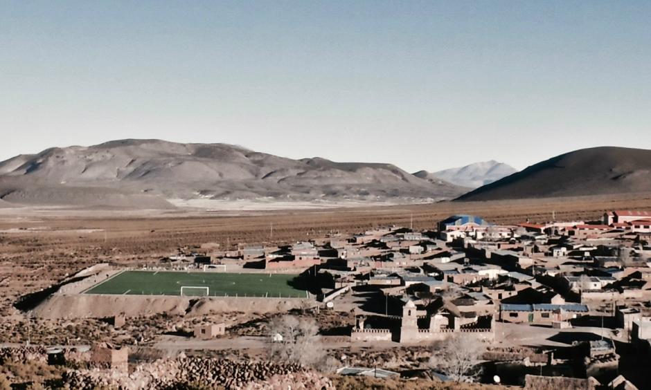 The population of Santiago K, which had been thriving with growing demand for quinoa, fell sharply as a drought lingered into a second year in Bolivia. The artificial surface of its soccer field stands out against the dry ground. Photo: Ben Walker