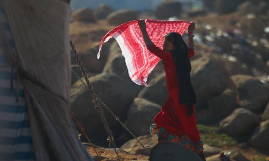 An internally displaced girl carries a scarf as she stands outside tents at a makeshift refugee camp in Sinjar town, in Idlib province, Syria, November 20, 2015. Photo: Ammar Abdullah, Reuters