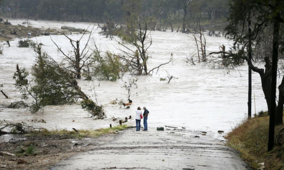 Jim Richardson and his wife Jeannette look on as the Blanco River recedes after the flash flood in Wimberly, Texas Friday, Oct. 30, 2015. A fast-moving storm packing heavy rain and destructive winds overwhelmed rivers and prompted evacuations Friday in the same area of Central Texas that saw devastating spring floods. Image credit: Ricardo Brazziell/Austin American-Statesman via AP.