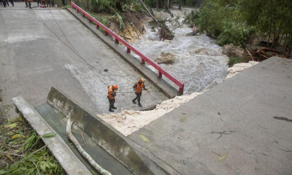 A handout picture made available by the National Coordination for Disaster Reduction of Guatemala (CONRED) shows members of the national army emergency and rescue team (UHR) working at a fallen bridge damaged after strong rains hit the region, following the passage of Tropical Storm Earl, in Melchor de Mencos, Guatemala, August 4, 2016. Photo: CONRED / EPA