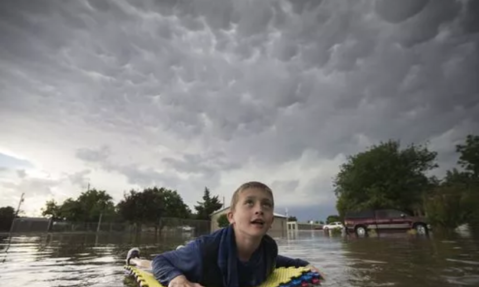 Kevin Weibe floats down his street in Scott City, Kan., while looking up at mammatus clouds after heavy rains inundated the small, western Kansas town on Tuesday, June 19, 2018. High heat will be the main weather story in the central U.S. over the next few days. Credit: Travis Heying, AP