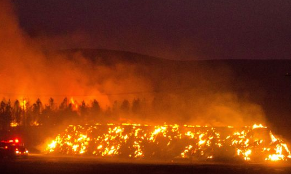 A firetruck moves along Highway 125 past a blazing stack of hay bales north of Walla Walla, Wash., during a large wildfire on Aug. 21, 2016. Photo: Greg Lehman, Walla Walla Union-Bulletin, via AP