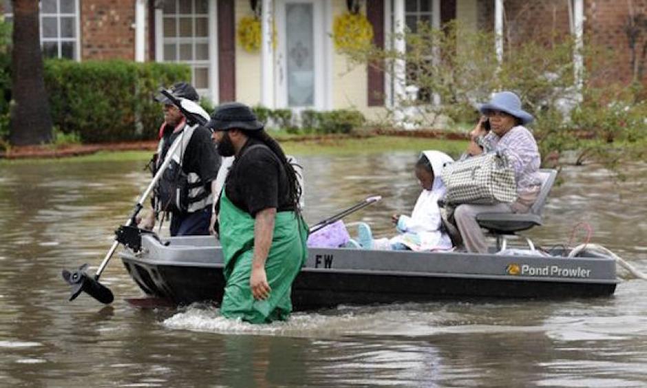 olunteers pull a boat with a woman and young child as they evacuate from their homes on Aug. 13, 2016, in Baton Rouge. Photo: John Oubre/The Advocate via AP