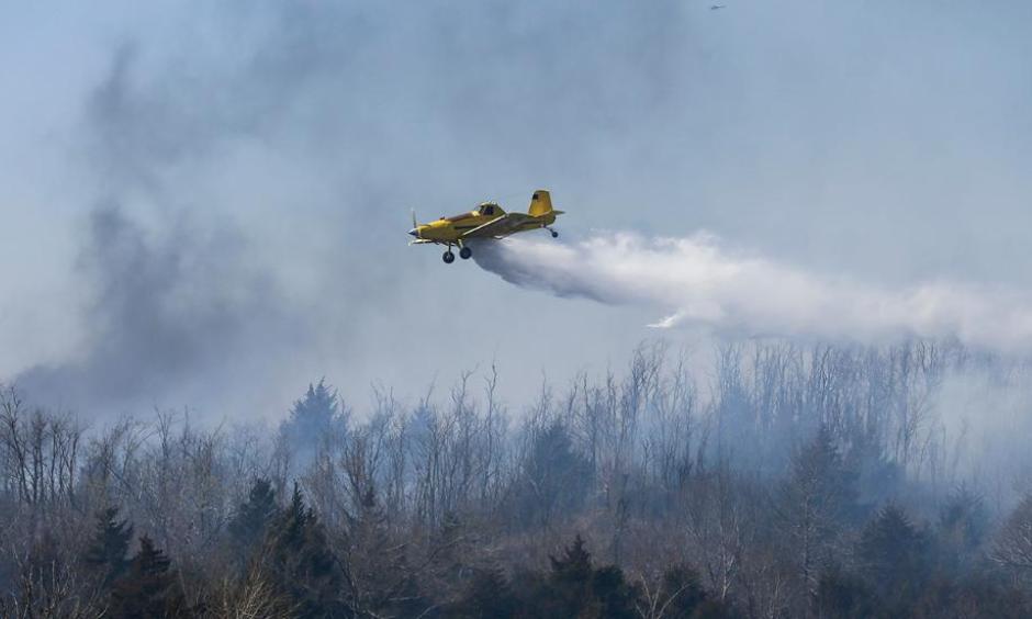 A crop duster drops water on a wildfire north of Hutchinson, Kan., on Tuesday, March, 7, 2017. Wildfires have erupted across the Kansas over the last 24 hours. Photo: Travis Heying, Wichita Eagle via AP