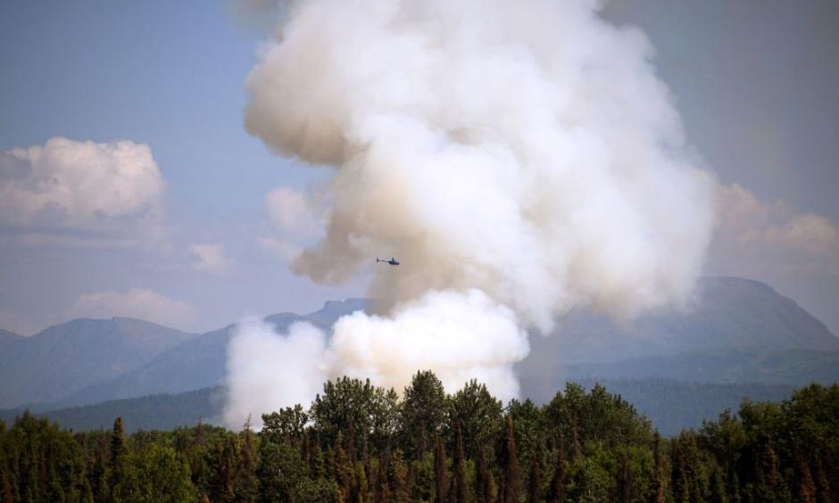 A helicopter passes by as smoke rises from a wildfire on July 3, 2019 south of Talkeetna, Alaska near the George Parks Highway. Credit: Lance King, Getty
