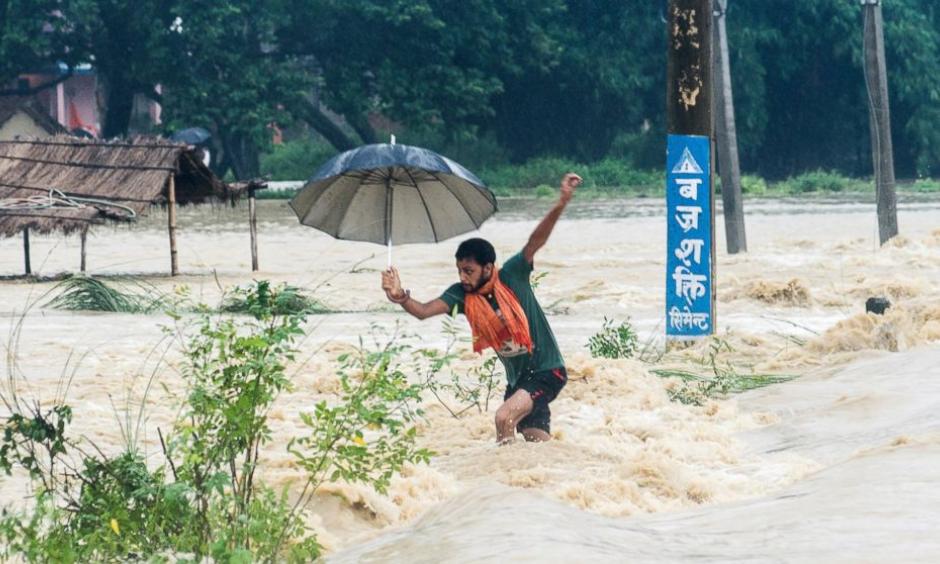 A Nepalese man looses his balance while crossing a flooded street in Birgunj, Nepal, Sunday, Aug. 13, 2017. An official said torrential rain, landslides and flooding have killed dozens of people in Nepal over the past three days, washing away hundreds of homes and damaging roads and bridges across the Himalayan country. Photo: Manish Paudel, AP