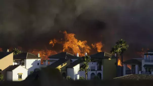 Homes with flames in the background.