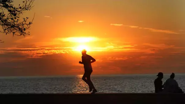 A hot yellow sun rises on Lake Michigan at Montrose Avenue Monday Sept. 25, 2017 as a jogger takes advantage of the cool early morning temperatures. Although still cool at sunrise another record-breaking hot day was expected for the Chicago area. Photo: Nancy Stone / Chicago Tribune