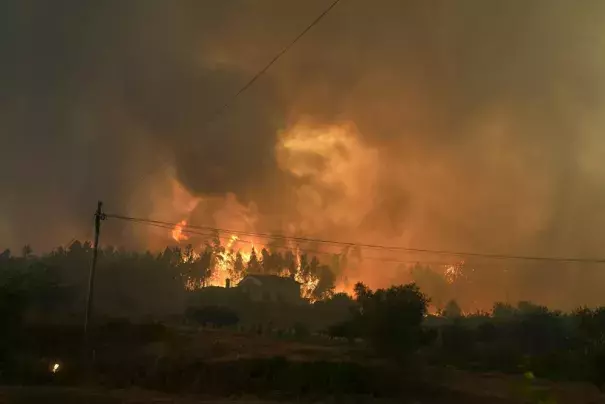 A forest fire closes on a house in the village of Bemposta, near Ansiao, central Portugal, Wednesday, July 13, 2022. Thousands of firefighters in Portugal continue to battle fires all over the country that forced the evacuation of dozens of people from their homes. (Credit: AP Photo/Armando Franca)