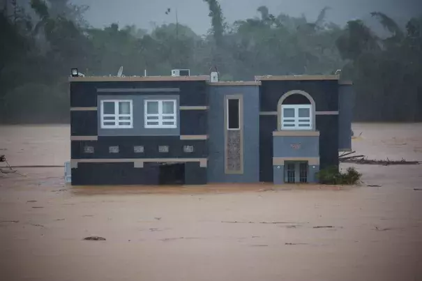 A home is submerged in floodwaters caused by Hurricane Fiona in Cayey, Puerto Rico, Sunday, Sept. 18, 2022. According to authorities three people were inside the home and were reported to have been rescued. (AP Photo/Stephanie Rojas)