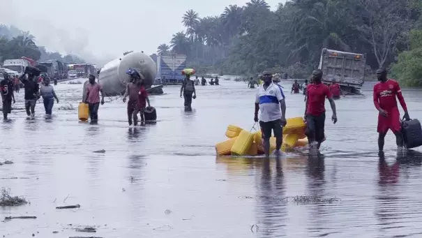 FILE- People wade through flooded roads in Bayelsa, Nigeria, Oct. 20, 2022. Climate change is to blame for the deadliest yet heavy rains and flooding that swamped Nigeria, Niger, Chad, and the neighboring Sahel region between the months of June and October leaving more than 800 people dead. (Credit: AP Photo/Reed Joshua, File)