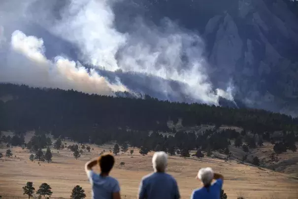 From left, Laura Tyson, Tod Smith and Rebecca Caldwell, residents of Eldorado Springs, watch as the NCAR fire burns in the foothills south of the National Center for Atmospheric Research, Saturday, March 26, 2022, in Boulder, Colo. The NCAR fire prompted evacuations in south Boulder and pre-evacuation warning for Eldorado Springs. (Credit: Helen H. Richardson/The Denver Post via AP, File) 