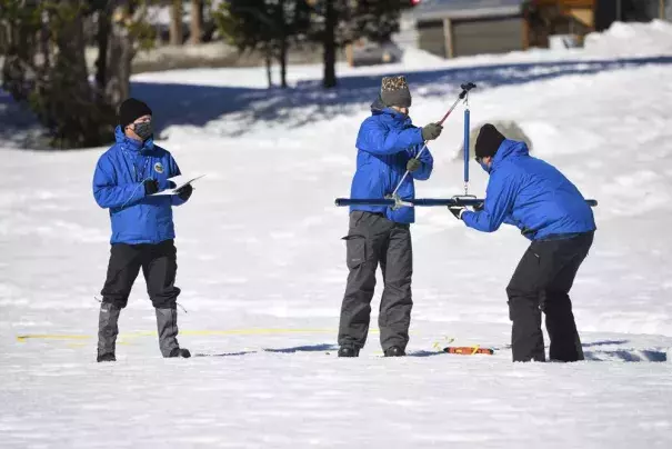 Sean de Guzman, chief of snow surveys for the California Department of Water Resources, right, places the snowpack measuring tube of a scale held by DWR's Anthony Burdock, center, as DWR's Andy Reising, left, looks on during the second snow survey of the season held at Phillips Station near Echo Summit, Calif., Tuesday, Feb. 1, 2022. The survey found the snowpack at 48.5 inches with 19 inches of snow water content. That's 109% of the historical average at this time of the year. But statewide, the water in t