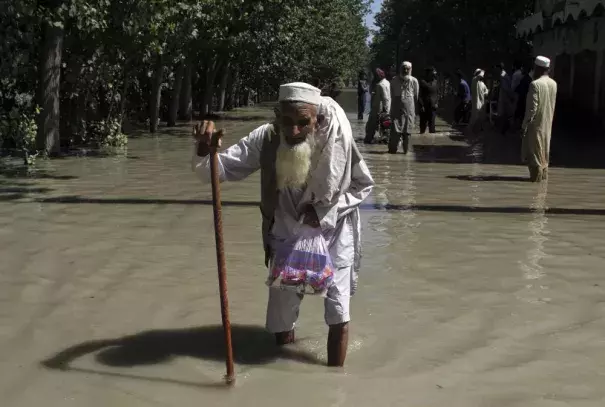 FILE - A displaced man wades through a flooded area after fleeing his flood-hit home, on the outskirts of Peshawar, Pakistan, Aug. 28, 2022. The flooding has all the hallmarks of a catastrophe juiced by climate change, but it is too early to formally assign blame to global warming, several scientists tell The Associated Press. (Credit: AP Photo/Mohammad Sajjad, File)