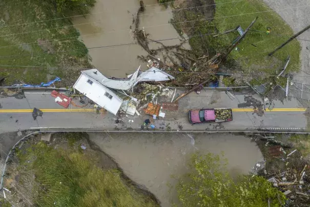 People work to clear a house from a bridge near the Whitesburg Recycling Center in Letcher County, Ky., on Friday, July 29, 2022. (Credit: Ryan C. Hermens/Lexington Herald-Leader via AP)