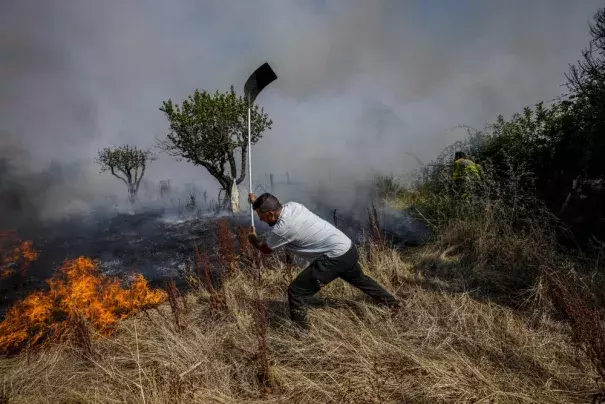 A local resident fights a forest fire with a shovel during a wildfire in Tabara, north-west Spain, Tuesday, July 19, 2022. Firefighters battled wildfires raging out of control in Spain and France as Europe wilted under an unusually extreme heat wave that authorities in Madrid blamed for hundreds of deaths. (Credit: AP Photo/Bernat Armangue)