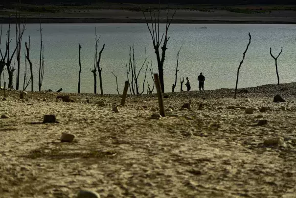 FILE - People walk close to the border at Yesa's reservoir affected by drought, on a sunny summer day in Yesa, around 55 kilometers (34,17 miles), from Pamplona, northern Spain, Sept. 14, 2022. Widespread drought that dried up large parts of Europe, the United States and China this past summer was made 20 times more likely by climate change, according to a new study. (AP Photo/Alvaro Barrientos)