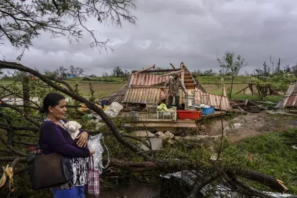 Mercedes Valdez holds her dog Kira as she waits for transportation after losing her home to Hurricane Ian in Pinar del Rio, Cuba, Tuesday, Sept. 27, 2022. (AP Photo/Ramon Espinosa)