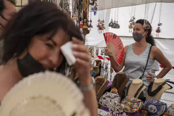 FILE - Women cool themselves with fans in the Rastro flea market during a heatwave in Madrid, Spain, Aug. 15, 2021. Scientists say last summer was the hottest summer on record in Europe, with temperatures a 1.8 Fahrenheit higher than the average for the previous three decades. A report released Friday, April 22, 2022 by the European Union’s Copernicus Climate Change Service found that while spring 2021 was cooler than average, the summer months were marked by “severe and long-lasting heatwaves.” (AP Photo)