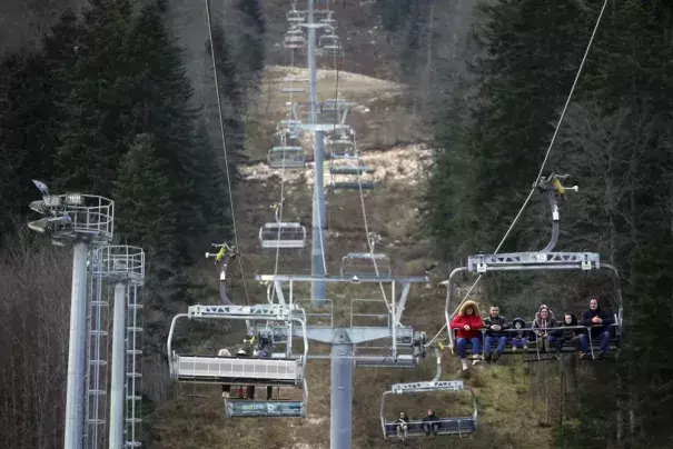 People ride the cable car above the ski track without any snow on Bjelasnica mountain near Sarajevo, Bosnia, Wednesday, Jan. 4, 2023. (Credit: AP Photo/Armin Durgut)