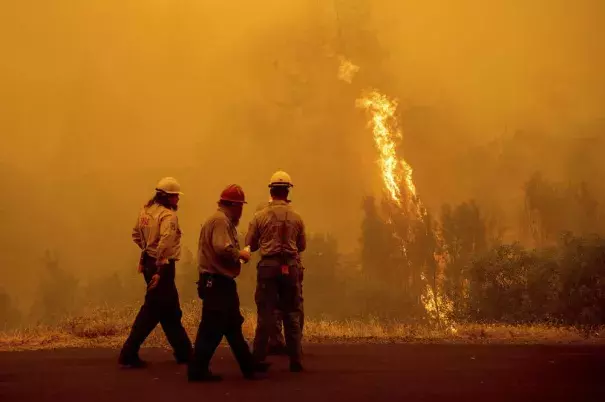 Flames from the McKinney Fire burn beyond firefighters in Klamath National Forest, Calif., on Sunday, July 31, 2022. (Credit: Noah Berger/AP)