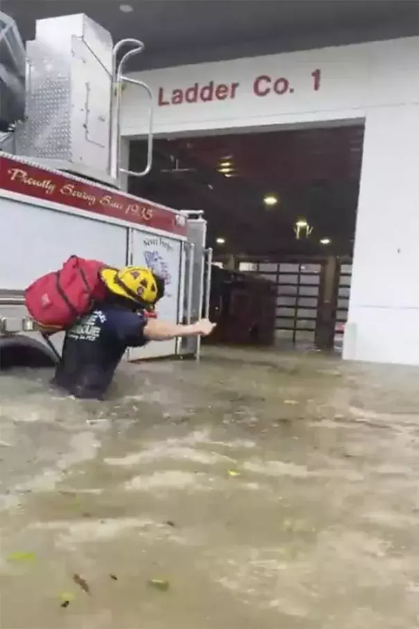 This image provided by the Naples Fire Rescue Department shows a firefighter carrying gear in water from the storm surge from Hurricane Ian on Wednesday, Sept. 28, 2022 in Naples, Fla. Hurricane Ian has made landfall in southwestern Florida as a massive Category 4 storm. (Naples Fire Department via AP)