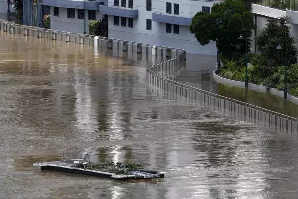 An unhinged pontoon drifts past apartments on the river in Brisbane, Australia, Wednesday, March 2, 2022. Tens of thousands of people had been ordered to evacuate their homes and many more had been told to prepare to flee as parts of Australia's southeast coast are inundated by the worst flooding in decades. (Credit: AP Photo/Tertius Pickard)
