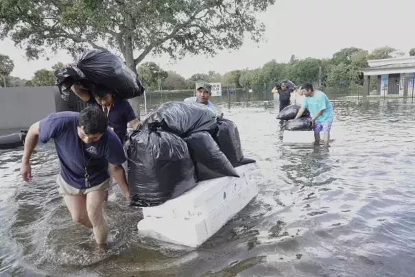 People try and save valuables, wading through high flood waters in a Fort Lauderdale, Fla., neighborhood on Thursday, April 13, 2023. South Florida is keeping a wary eye on a forecast that calls for rain a day after nearly a foot fell in a matter of hours. The rains caused widespread flooding, closed the Fort Lauderdale airport and turned thoroughfares into rivers. (Credit: Joe Cavaretta/South Florida Sun-Sentinel via AP)