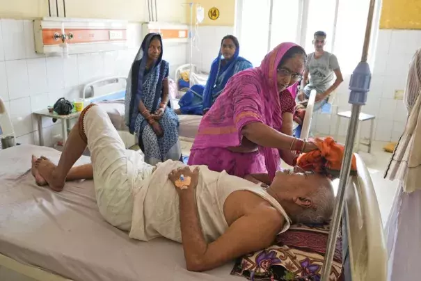 Shiela Mishra wipes the head of her ailing brother to keep him cool from the heat wave by using a wet cloth at the district hospital in Ballia, Uttar Pradesh state, India, Monday, June 19, 2023. Several people have died in two of India's most populous states in recent days amid a searing heat wave, as hospitals find themselves overwhelmed with patients. More than hundred people in the Uttar Pradesh state, and dozens in neighboring Bihar state have died due to heat-related illness. (Credit: AP Photo/Rajesh K