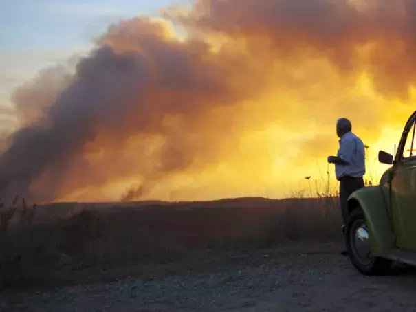 A man watches as smoke from a wildfire rises into the sky. Photo: Uriel Sinai, Getty Images