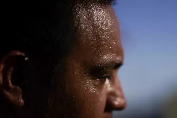 Sweat covers the face of Juan Carlos Biseno after dancing to music from his headphones as afternoon temperatures reach 115 degrees Fahrenheit (46.1 Celsius) July 19, 2023, in Calexico, Calif. (Credit: AP Photo/Gregory Bull)