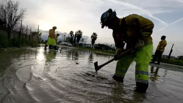 A Cal Fire crew member is shown standing in water, working to build a trench.