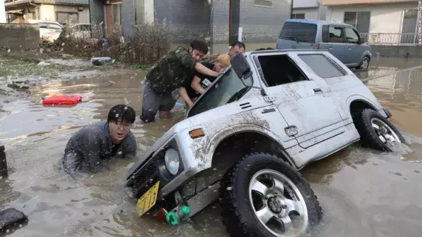 Residents try to upright a vehicle stuck in a flood hit area in Kurashiki, Okayama prefecture on July 9, 2018. Credit: CNN