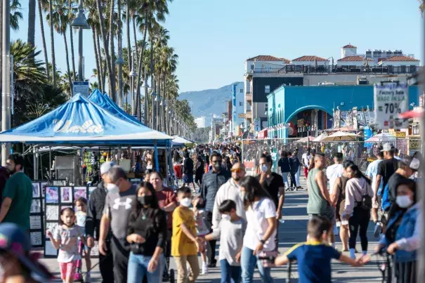 People walk along the Venice Beach Boardwalk on Feb. 6, 2022, in Los Angeles. (Credit: Alexi Rosenfeld / Getty Images)