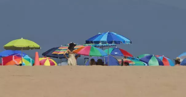 Beachgoers camped out under umbrellas at Manhattan beach this summer. A heat wave is expected to push Southern California temperatures into the triple digits. Photo: John Antczak, Associated Press