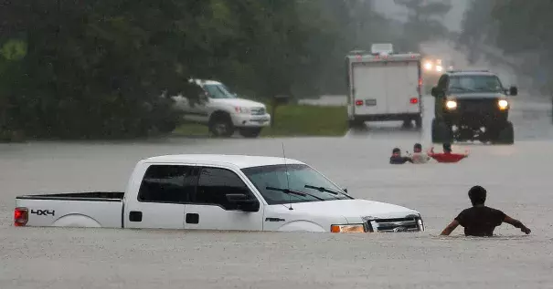 The three men in the foreground had to abandon their truck Friday after getting caught in rising flood waters in Magnolia, Tex. Photo: Michael Ciaglo, Houston Chronicle, via Associated Press