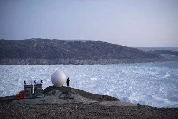 A researcher looks over the Helheim glacier in Greenland. Climate change is pushing the world toward dangerous tipping points, scientists warned in a new report. (Credit: Felipe Dana/AP)