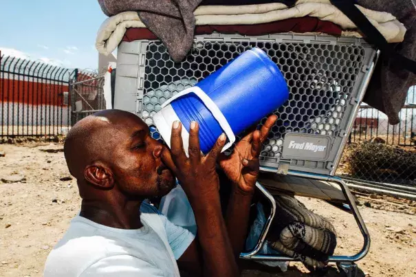 Desmont Smith sits in the shade of his shopping cart drinking water in Phoenix. Credit: Ann Johansson, Corbis via Getty Images