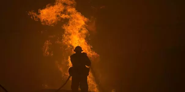 A firefighter hoses down burning pipes near a water tank. Photo: David McNew/Getty Images 