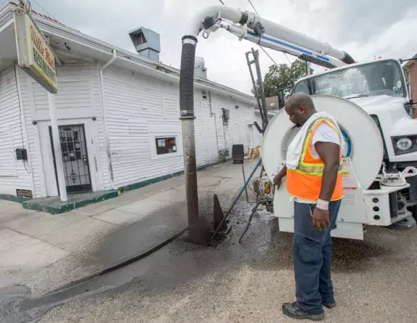 A New Orleans city worker sprays out mud and debris from a storm drain at Wille Mae's Restaurant before the governor toured it and other businesses damaged by Saturday's flash flooding in New Orleans, La. Monday, Aug. 7, 2017. Photo: Matthew Hinton