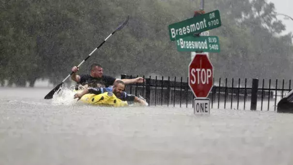 Two kayakers try to beat the current pushing them down an overflowing Brays Bayou from Tropical Storm Harvey in Houston, Texas, Sunday, Aug. 27, 2017. Photo: Mark Mulligan/Houston Chronicle via AP