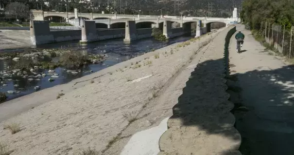 A cyclist rides along recently installed temporary flood control walls along the L.A. River in Los Angeles Friday, Feb. 12, 2016. Ten days with record heat and no rain have Californians worrying about the drought again. Photo: Damian Dovarganes, AP