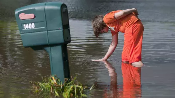 Logan Krevchuck, 14, puts his hand in a whirlpool as flood waters drained along Second Street Northwest in Waseca, Minn., Thursday. Photo: Jackson Forderer for MPR News