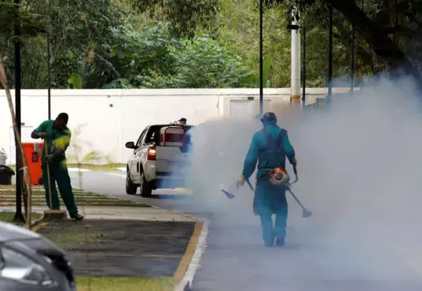 A truck sprays insecticide near grounds workers at Olympic media accommodations as part of preventative measures against the Zika virus and other mosquito-borne diseases in Rio de Janiero, Brazil. Photo: Chris Helgren, Reuters