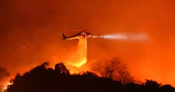 A Los Angeles County Firehawk copter makes a water drop on flames off CA Highway 154 north of Foothill Road. Credit: Mike Eliason / Santa Barbara County Fire