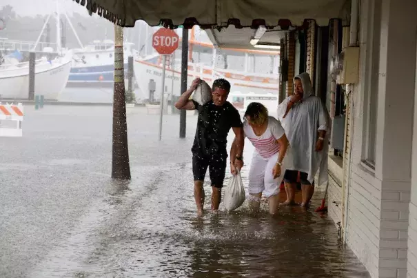 Angelo Memiakis, left, and Kelly Spiliotis work to deliver sandbags to the door jams of businesses along flooded Athens Street on Monday, June 6, 2016, in Tarpon Springs, FL, as Tropical Storm Colin barreled up the west coast of Florida. Photo: Douglas R. Clifford/The Tampa Bay Times via AP