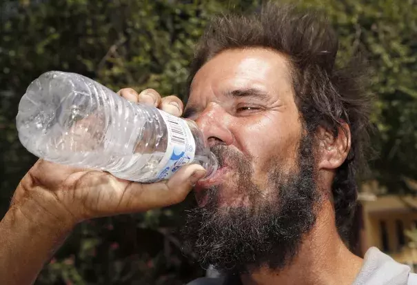 Michael Martinez drinks a bottle of water at a Salvation Army hydration station in an effort to beat rising temperatures in Phoenix on Monday, July 20, 2016. Phoenix set daily record highs of 118°F on Sunday and 116°F on Monday, which were the earliest readings above 115°F in city history. Photo: Ross D. Franklin, AP