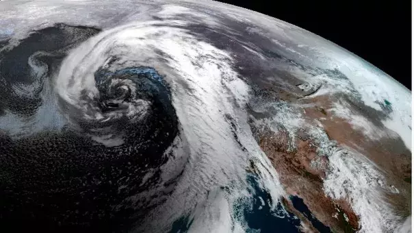 Satellite view of a large, comma-shaped storm system swirling over the northeast Pacific Ocean, dragging an atmospheric river into California. (Credit: NOAA via Axios)
